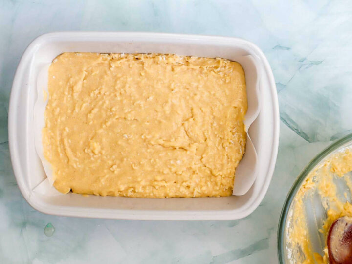 Coconut cake batter spread evenly in a lined baking dish.