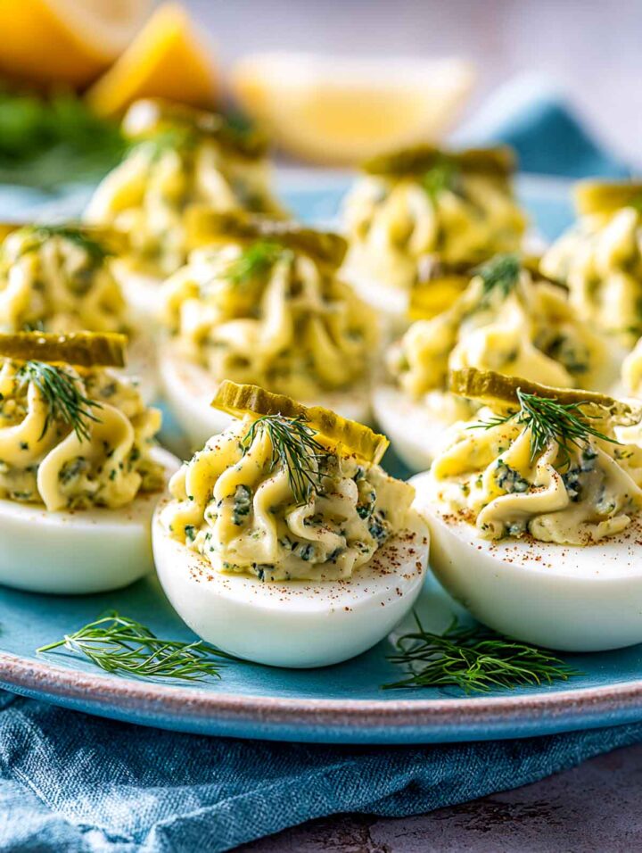 Dill pickle deviled eggs with pale yellow filling speckled with herbs.