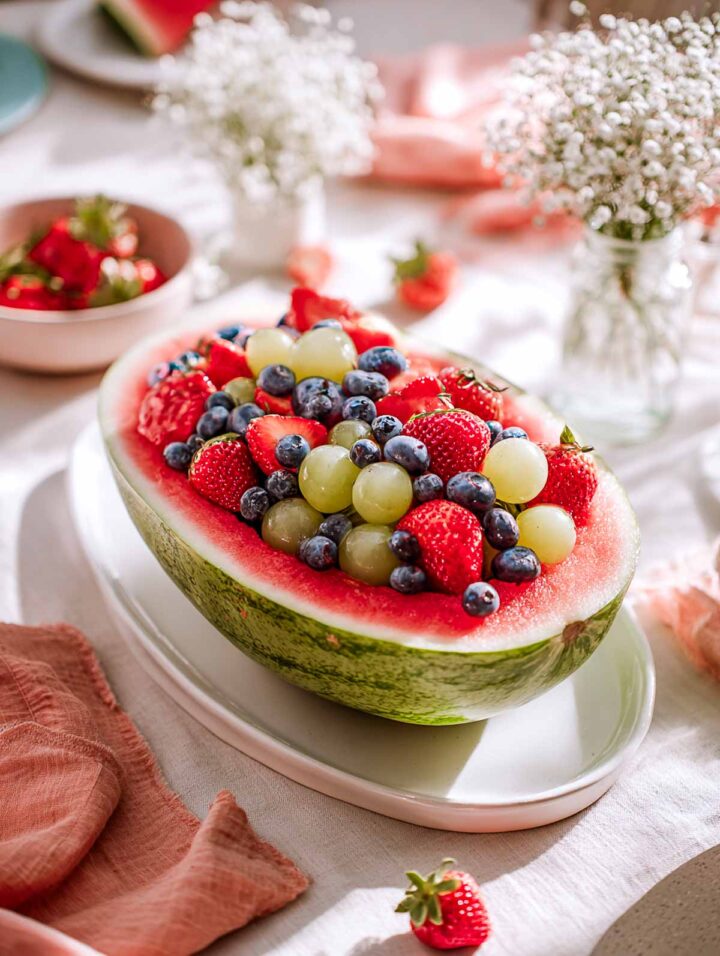 Fresh fruit baby carriage made with a halved watermelon filled with berries.