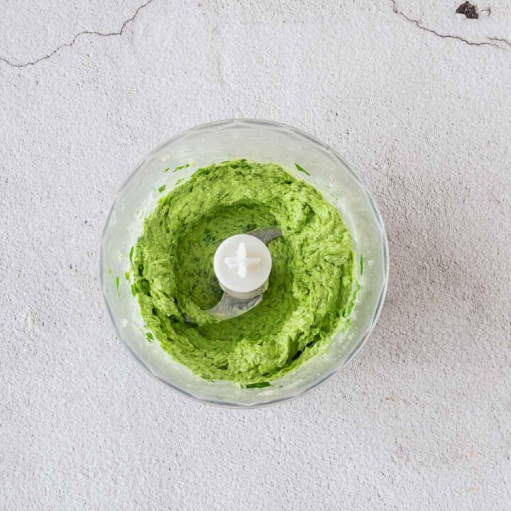 The fresh basil and garlic are processed into a thick, vibrant green paste, which serves as the flavor base for the sauce.