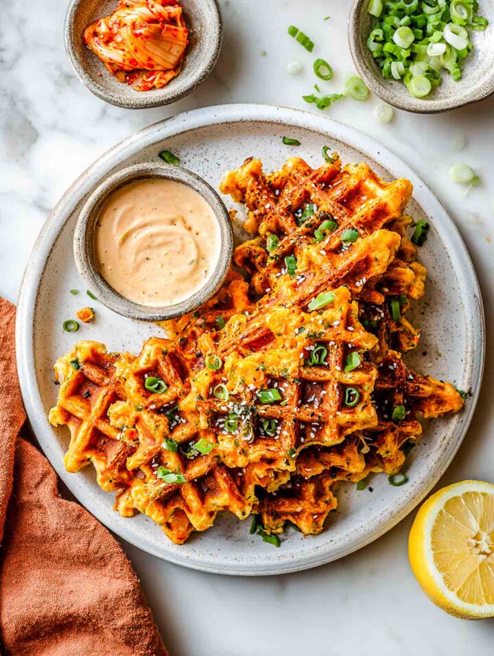 Snack-size kimchi cheddar chickpea waffles served with creamy dipping sauce.