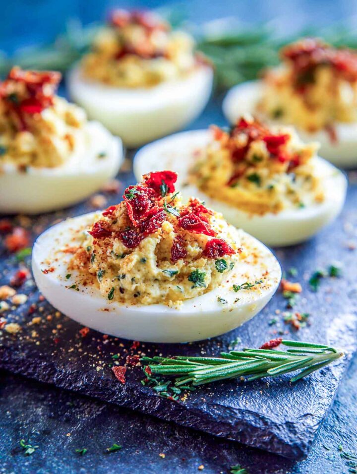 Creamy sun-dried tomato parmesan deviled eggs topped with savory tomato bits.