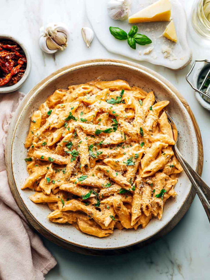 Close up of a bowl of creamy marry me pasta on a white marble surface.
