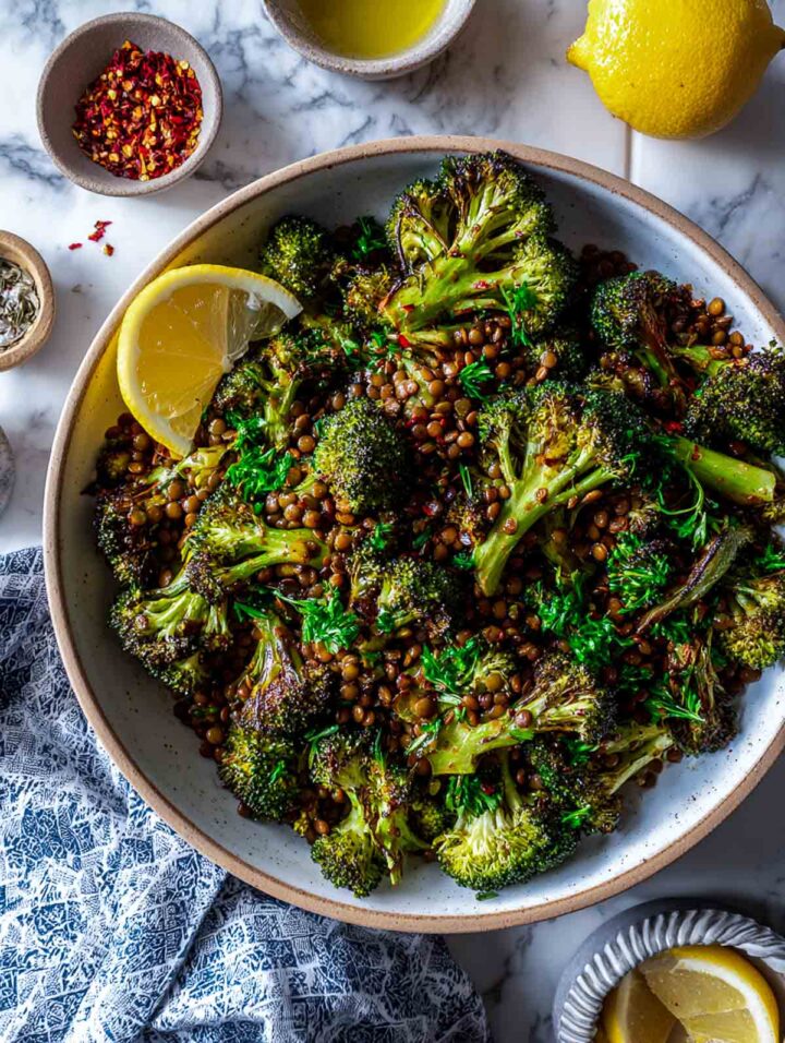 Roasted broccoli and lentils tossed with herbs in a large serving bowl.
