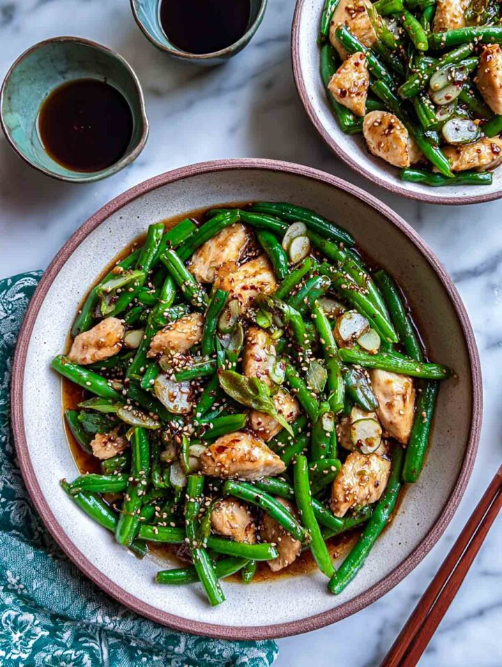 Sesame ginger chicken cooked with green beans in a skillet and served in bowls.