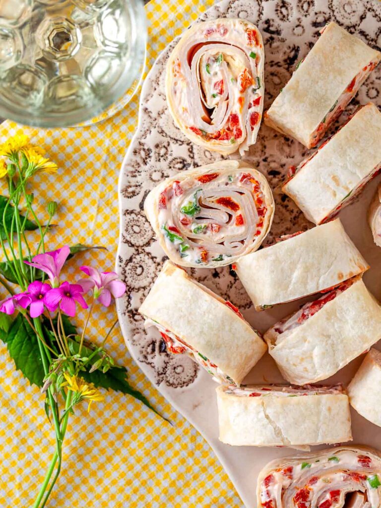 Sliced turkey and sun-dried tomato pinwheels on a serving plate.
