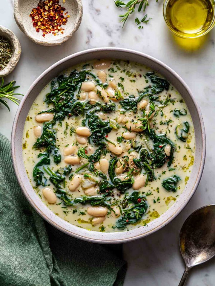 A bowl of Tuscan white bean soup with spinach and herbs.