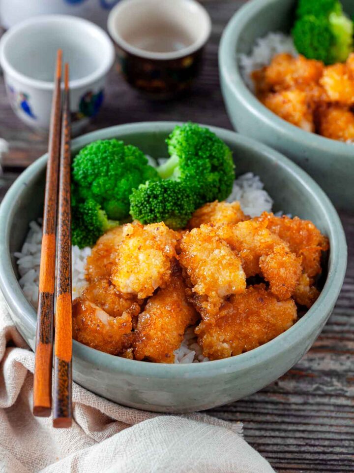 Side view of baked orange chicken served with broccoli and rice.