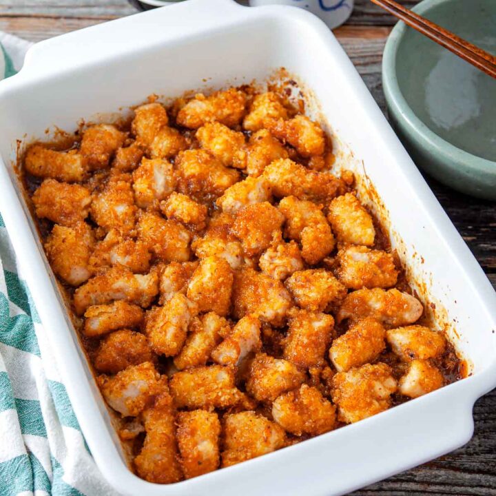 Crispy orange chicken baked in a white casserole dish.