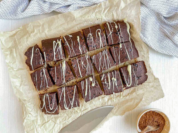 Beer brownies cut into squares and drizzled with white chocolate on parchment paper, ready to serve
