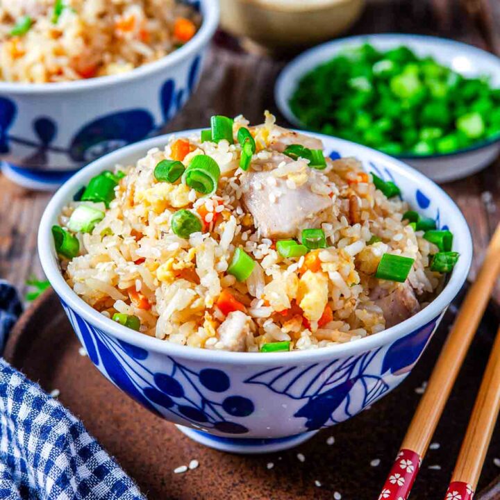 Bowl of chicken fried rice with scrambled eggs, carrots, and green onions.