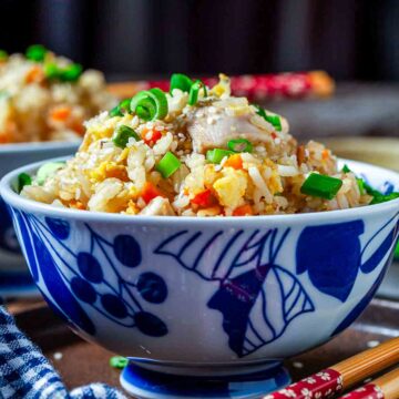 Close-up of chicken fried rice topped with green onions in a blue bowl.