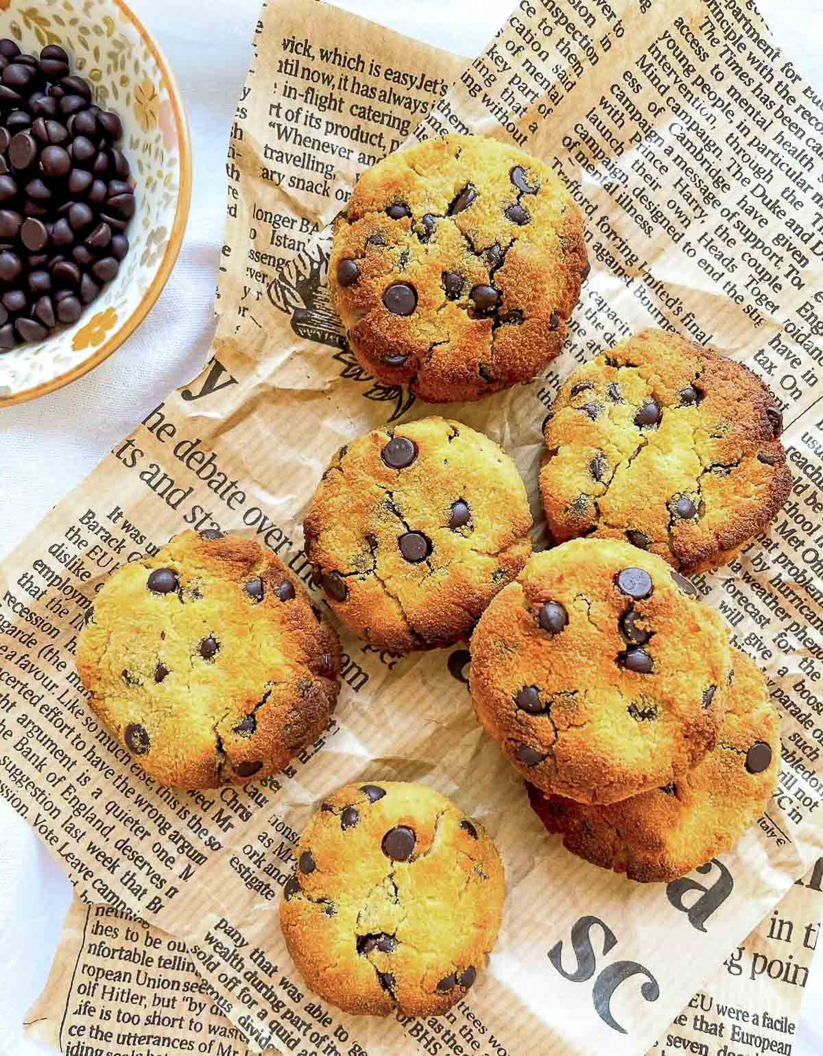 Coconut flour chocolate chip cookies arranged on parchment-style paper, golden brown with cracked tops and scattered chocolate chips