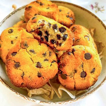 Coconut flour chocolate chip cookies in a bowl, one cookie broken open showing a soft, chocolate-studded center