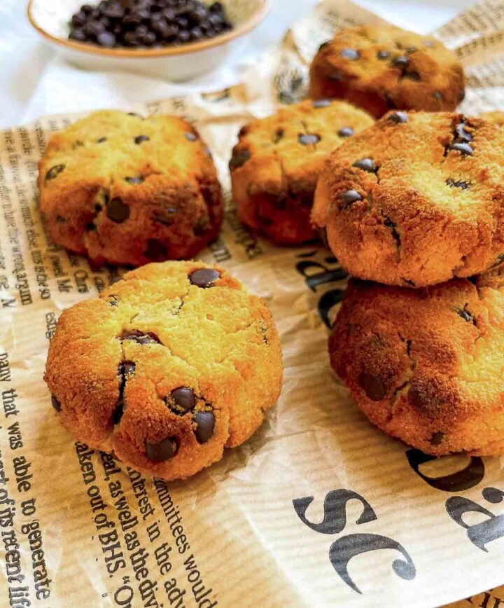 Side view of coconut flour chocolate chip cookies arranged on parchment-style paper, golden brown with cracked tops and scattered chocolate chips