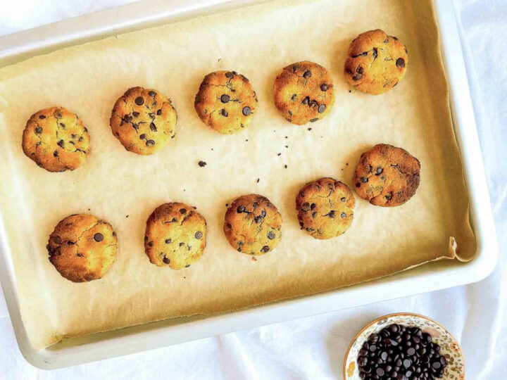 Freshly baked coconut flour chocolate chip cookies cooling on a parchment-lined baking sheet