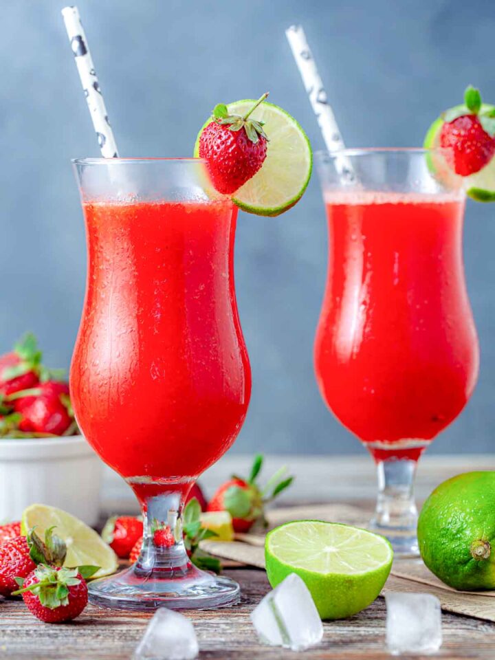 Frozen strawberry daiquiris with lime slices and fresh strawberries.