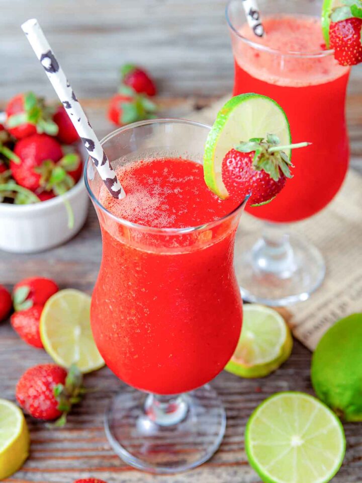Frozen strawberry daiquiris with lime and strawberry garnish.
