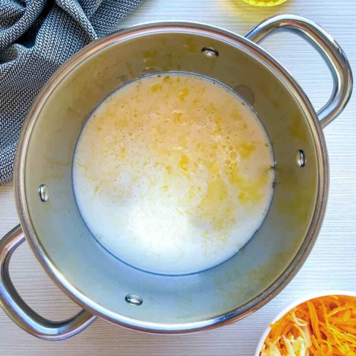 Milk and butter heating together in a pot for cheese sauce.