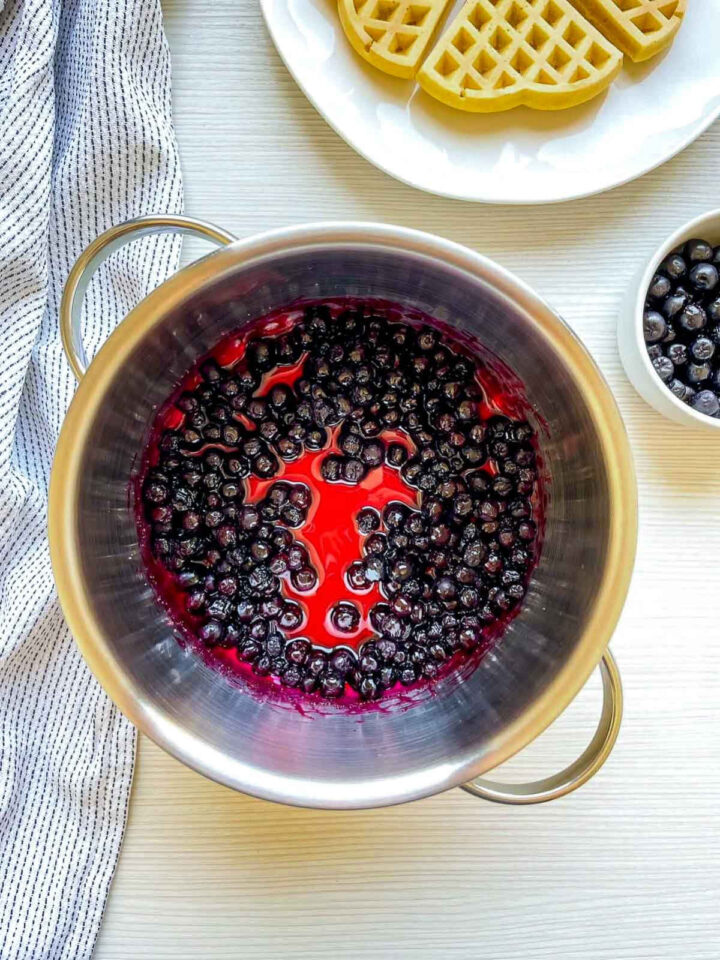 Blueberries simmering in a pot, creating a vibrant homemade compote.