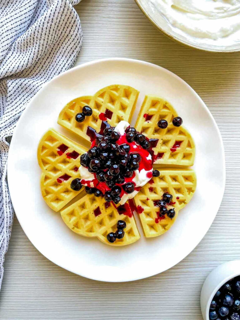 Finished lemon blueberry cheesecake waffle topped with creamy filling and sweet blueberry compote.