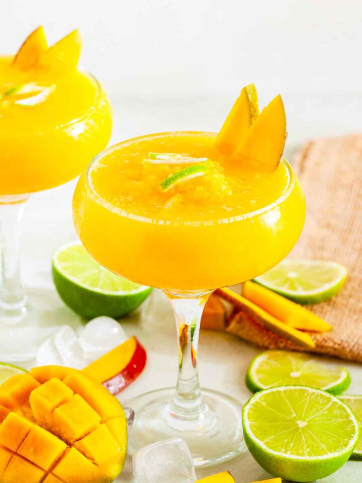 Frozen mango daiquiri garnished with mango slices and lime.
