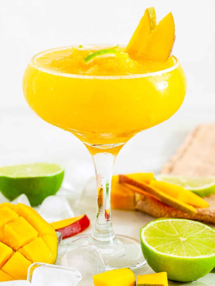 Frozen mango daiquiri garnished with mango slices and lime.