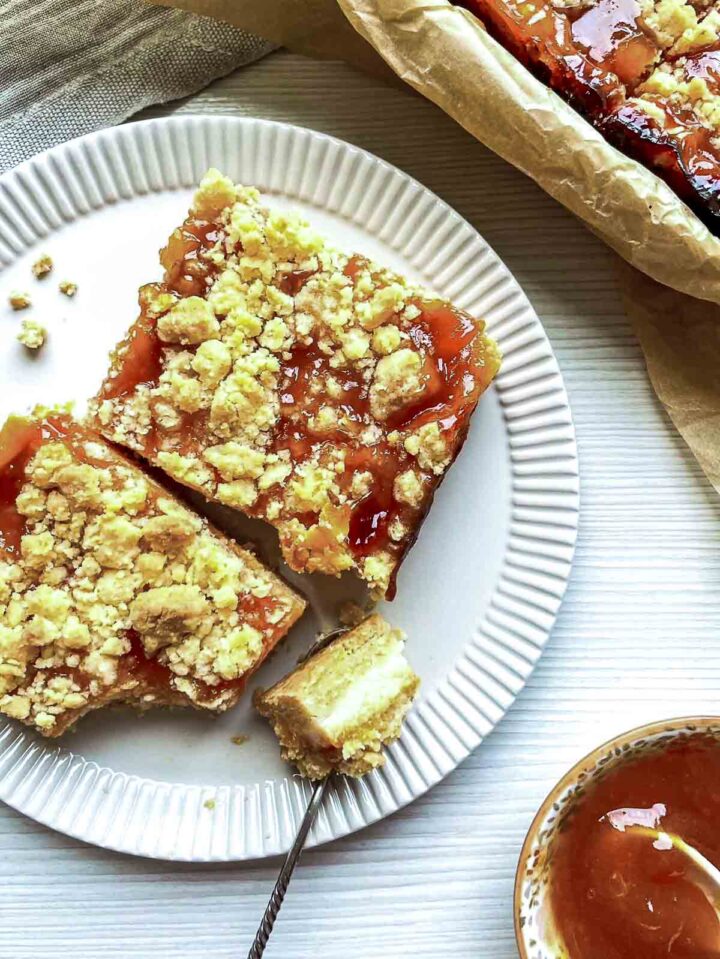 Close up of peach and cream crumble served on a white plate with a spoonful of the bar ready to eat.