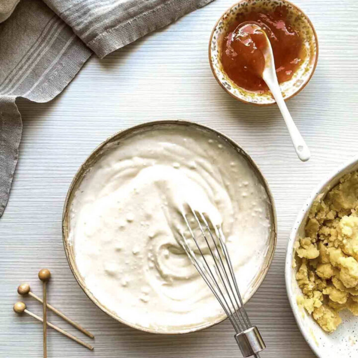 Cream cheese filling being whisked in a bowl beside peach jam and crumble mixture.