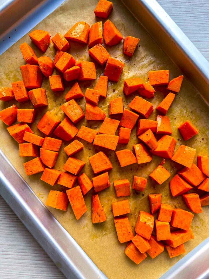 Roasted sweet potato cubes spread on a baking sheet.