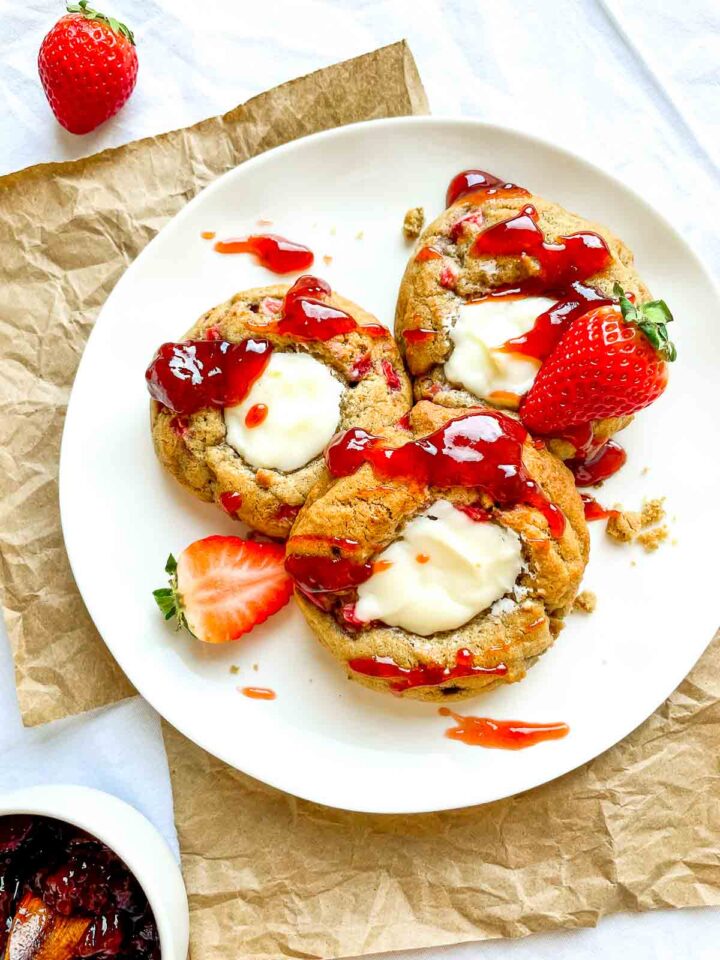 Strawberry cheesecake cookies drizzled with strawberry sauce on a white plate