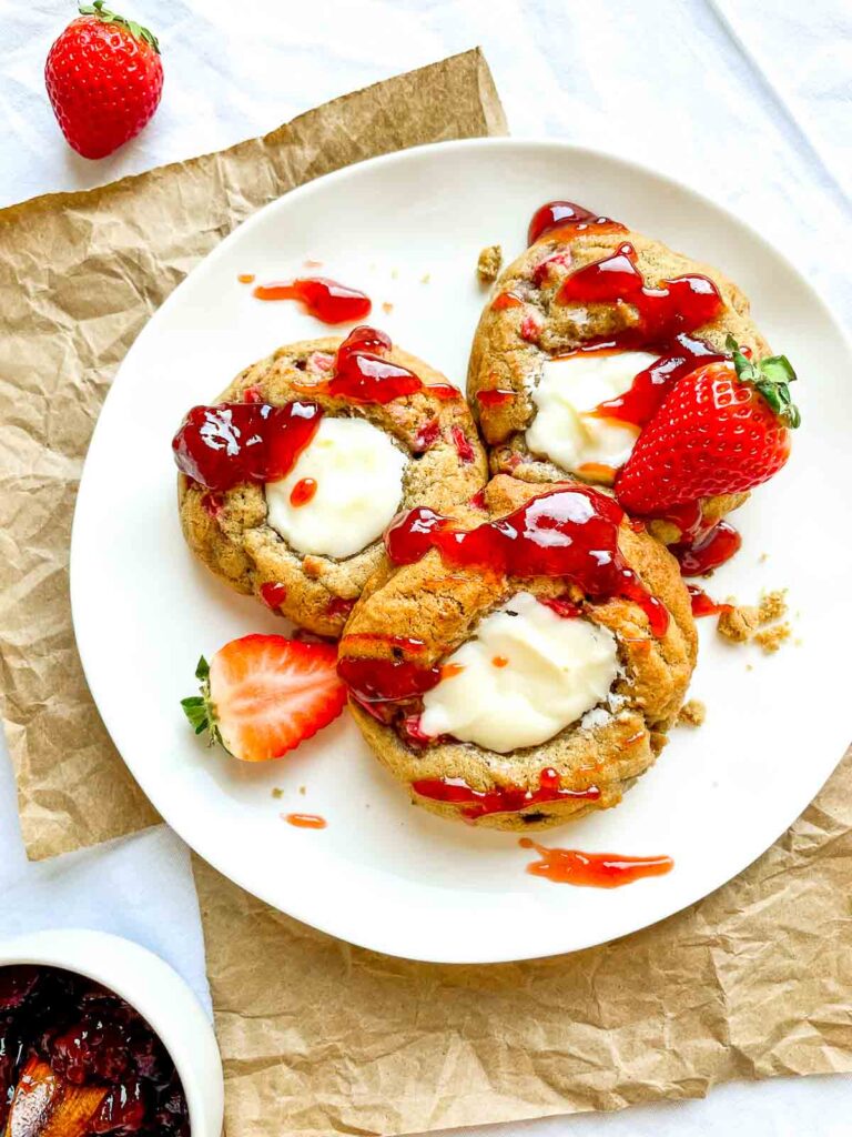 Strawberry cheesecake cookies drizzled with strawberry sauce on a white plate