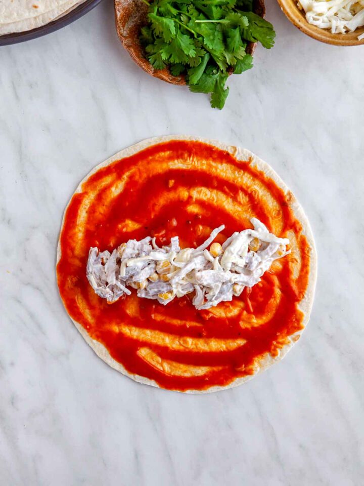 Flour tortilla spread with red enchilada sauce and filled with shredded chicken mixture.