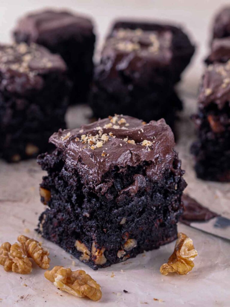Chocolate walnut brownie square with chocolate frosting and chopped walnuts.