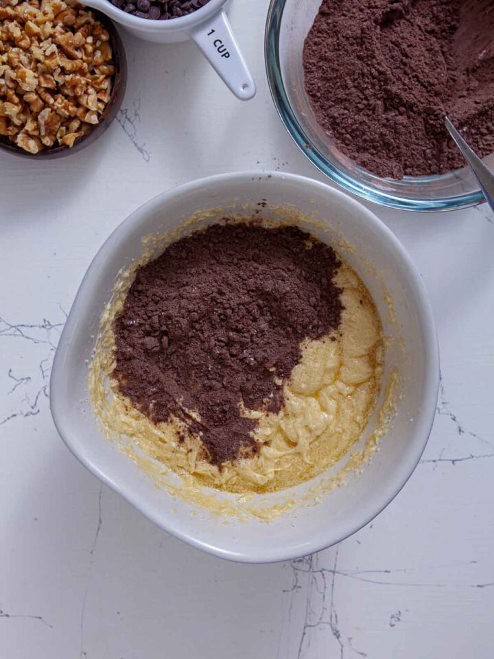 Cocoa powder mixture being added to creamed butter and sugar for brownie batter.