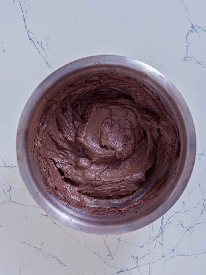 Smooth chocolate frosting being mixed in a bowl for brownies.