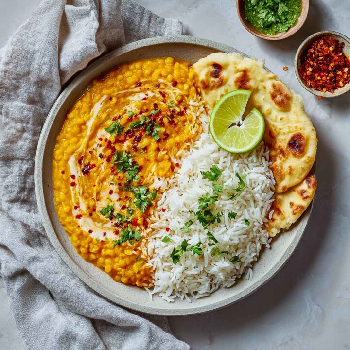 Creamy red lentil dal served with white rice and naan, finished with yogurt drizzle and fresh cilantro.