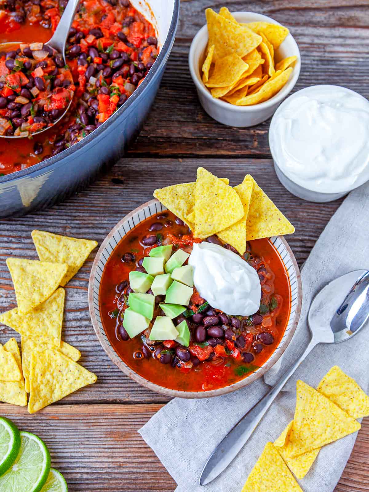 Bowl of black bean nacho soup topped with avocado, sour cream, and tortilla chips.