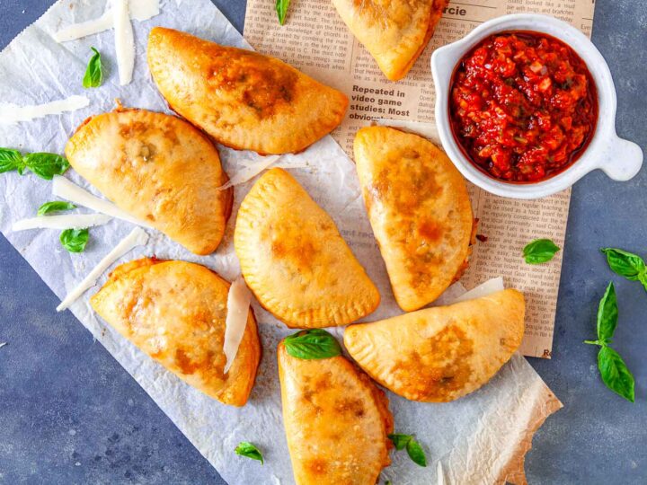 Baked pizza pockets placed on a white parchment paper.