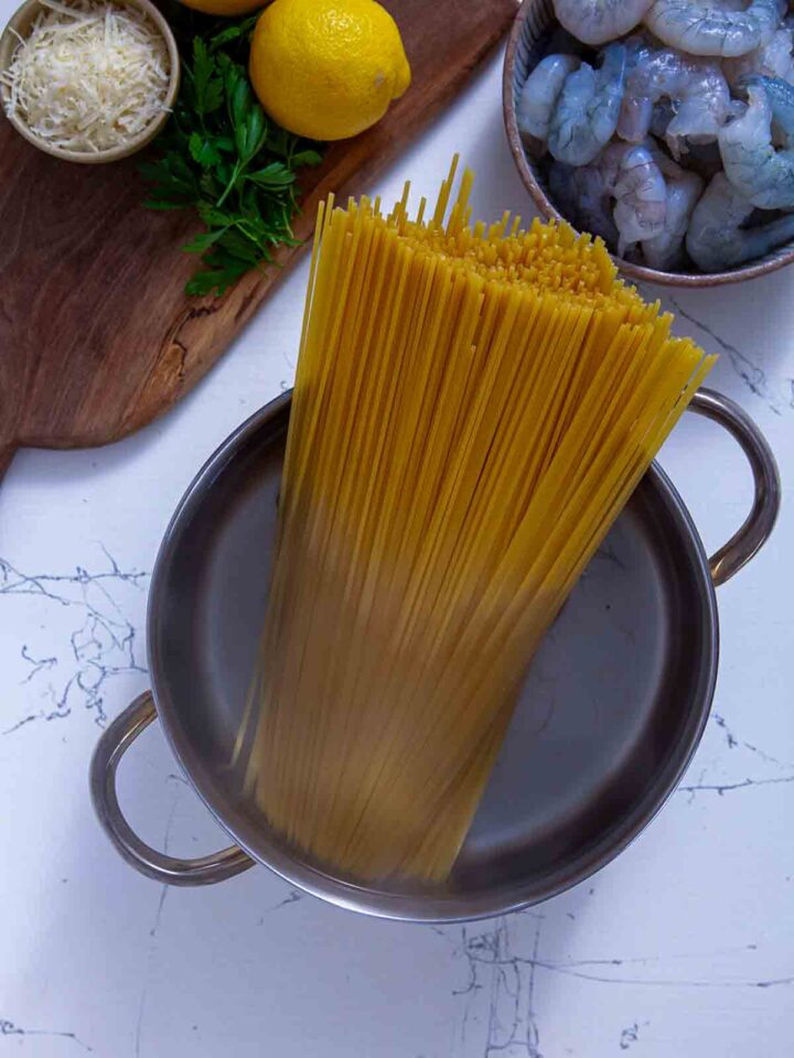 Dry spaghetti being added to a pot of boiling water for cooking.