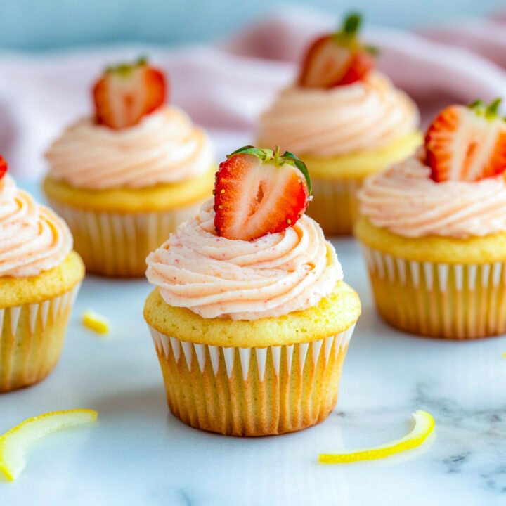 Side view of strawberry lemonade cupcakes on a white marble surface.