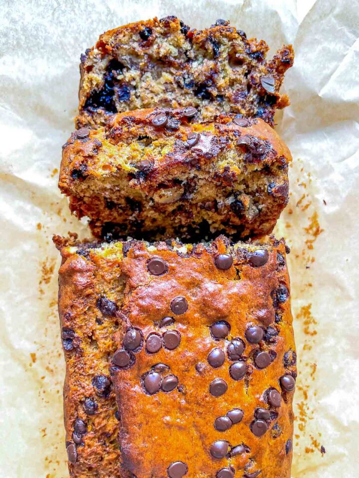 A freshly baked loaf of banana bread packed with melty chocolate chips and almonds, with a soft, moist interior and golden, slightly crisp top.