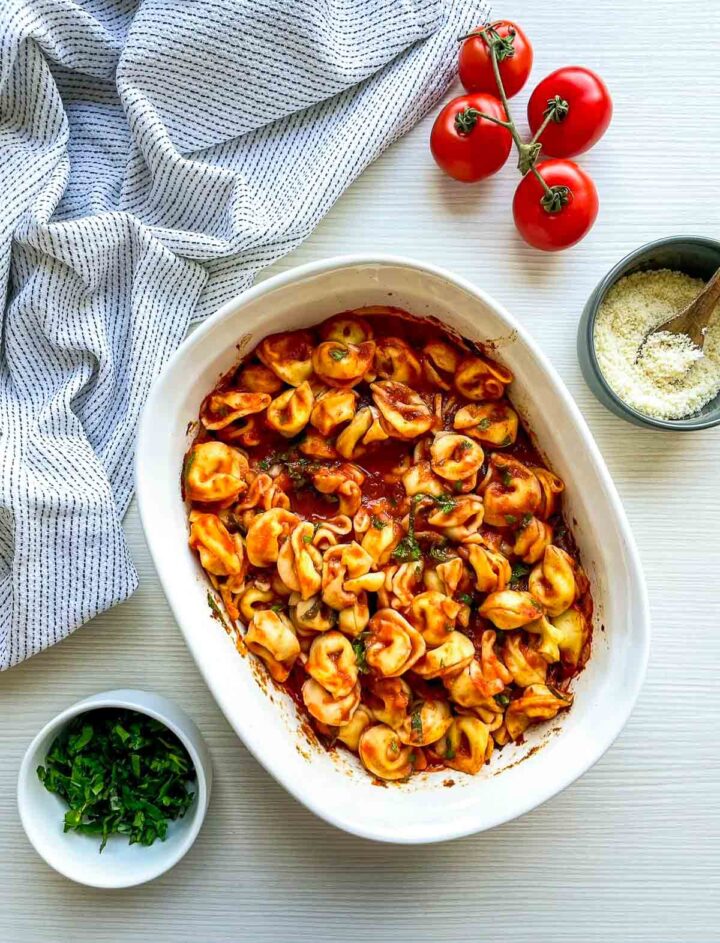 Tortellini coated in rich marinara sauce and herbs, mixed evenly in a baking dish before adding cheese.