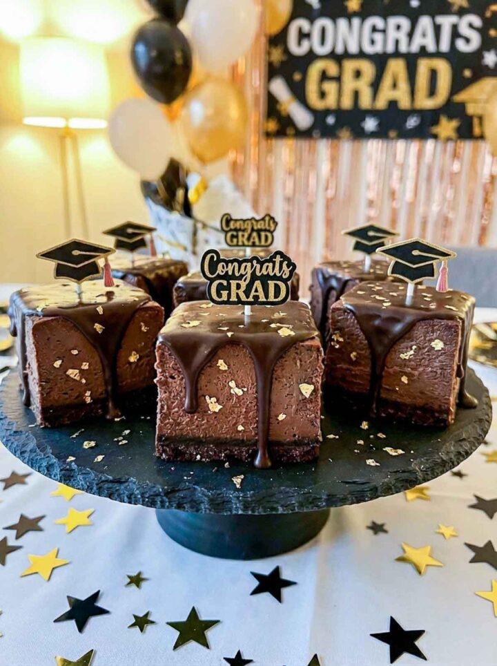 Cheesecake bars made placed on a cake stand and decorated with gold leaf.