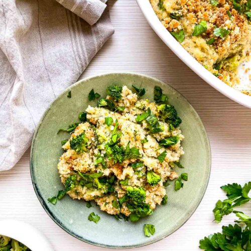 A warm serving of broccoli cheddar quinoa gratin, scooped onto a plate with crispy topping, tender broccoli, and fresh herbs for a wholesome, comforting bite.
