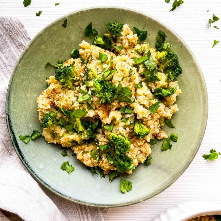 A warm, cheesy serving of broccoli cheddar quinoa gratin, topped with crispy crumbs and fresh herbs for a wholesome, comforting dish.