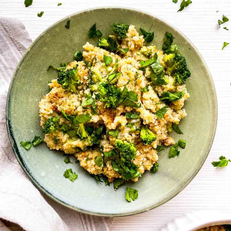 A warm, cheesy serving of broccoli cheddar quinoa gratin, topped with crispy crumbs and fresh herbs for a wholesome, comforting dish.
