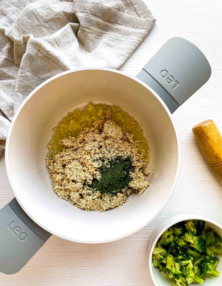 Quinoa simmering with broth and herbs, creating a flavorful base before combining with broccoli and cheese for the gratin.