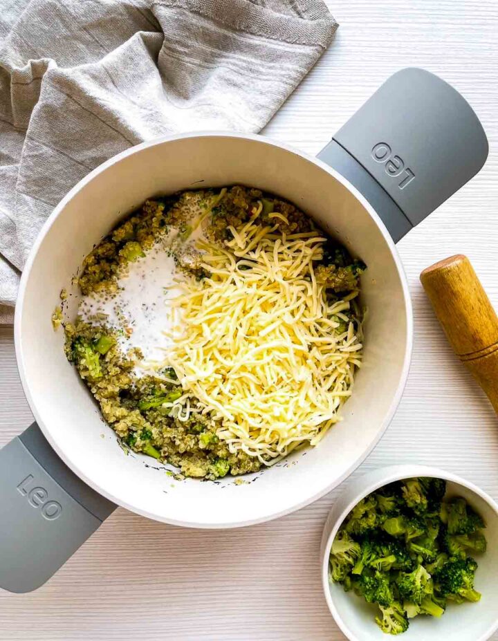 Tender cooked quinoa topped with vibrant broccoli florets, ready to be mixed into a hearty, cheesy gratin.