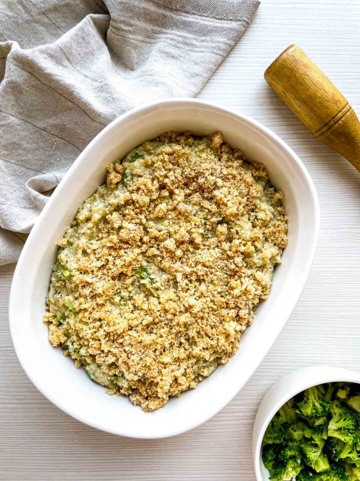 Broccoli gratin in baking dish topped with buttered parmesan breadcrumbs ready to bake